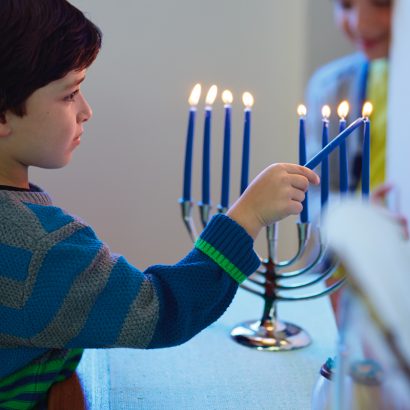 Boy lighting candle at hanukkah