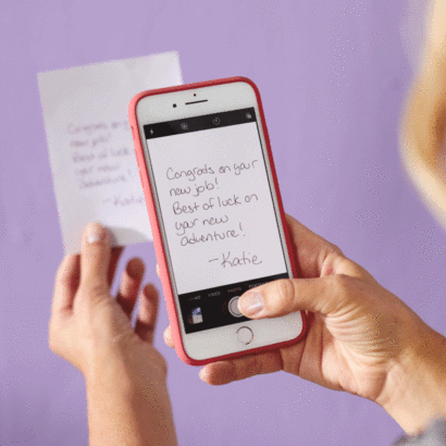 Hand holding phone taking a picture of a message on a piece of paper